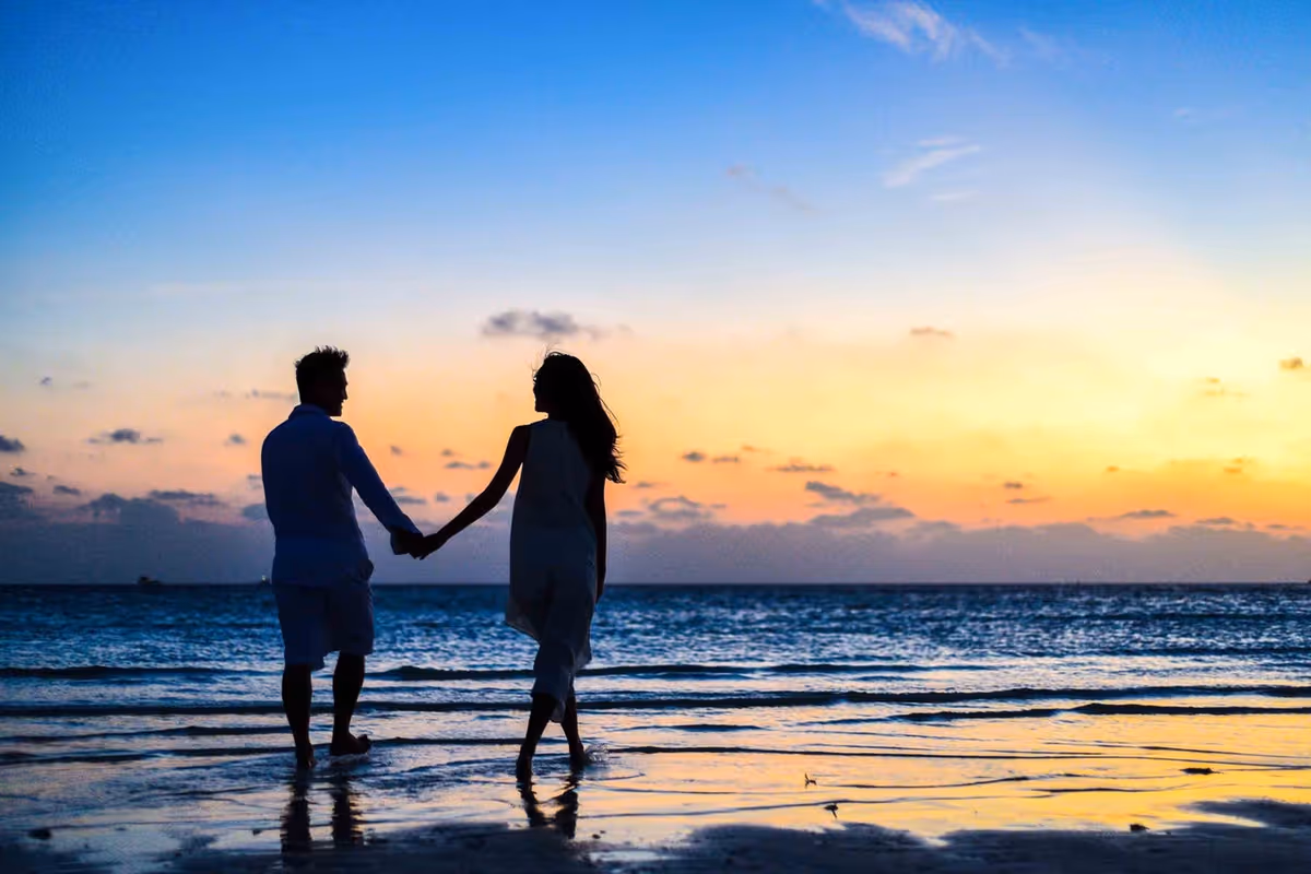 Couple holding hands walking on seashore
